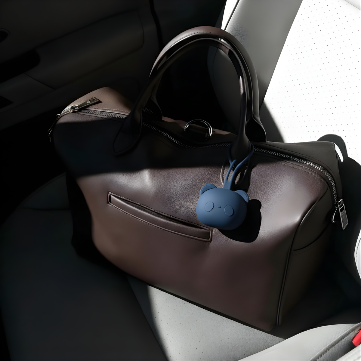 Porte-tétine en silicone bleu marine accroché au sac à langer HelloBiboo marron dans une voiture